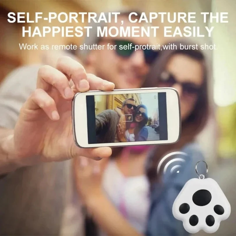 Paw-shaped GPS tracker used as remote camera shutter for selfies, showing group photo capture with wireless device

